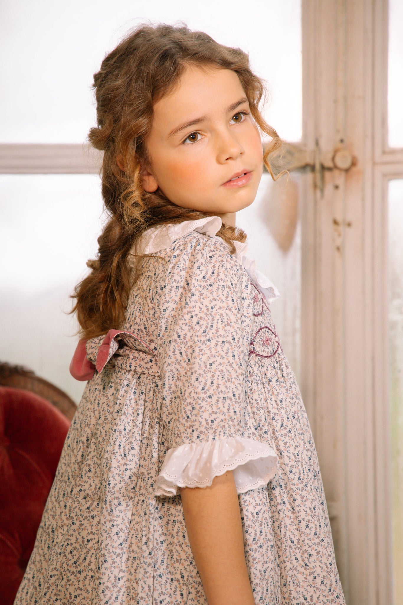 Young girl in Isadora Floral Long Sleeve Smocked Dress standing indoors